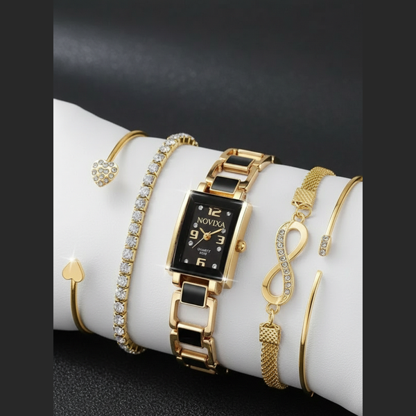 Gold watch and bracelets on a white surface with a black background